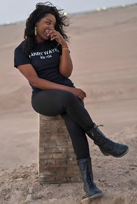 Portrait of young woman sitting on sand at beach