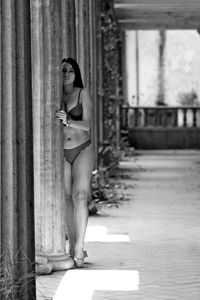 Lingerie model standing by column in abandoned corridor