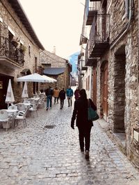 Rear view of women walking on street amidst buildings