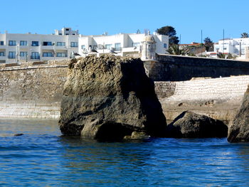 Sea by buildings against clear blue sky