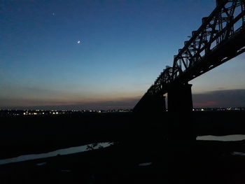 Silhouette of illuminated city against sky at night