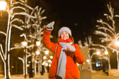 Midsection of woman standing in snow at night