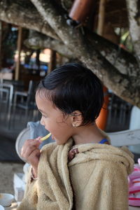 Girl eating food while sitting outdoors