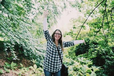 Portrait of carefree woman standing in forest