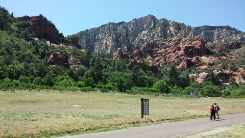 Rear view of man walking on road against rocky mountains