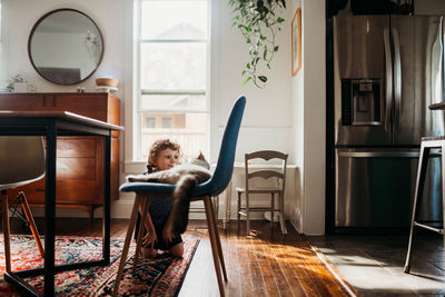 Preschool age girl sitting in dining room floor with pet cat