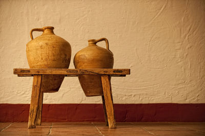 Close-up of vase on table against wall