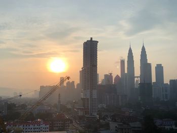 Modern buildings in city against sky during sunset