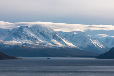 Scenic view of snowcapped mountains and sea against sky