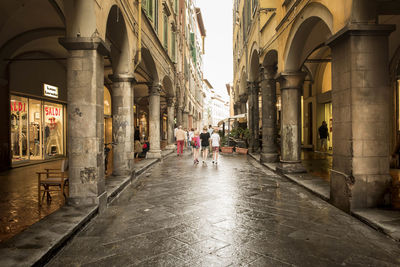 Rear view of people walking in alley amidst buildings at old town