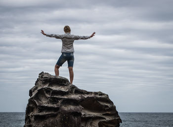 Woman standing at the coast with her arms outstretched