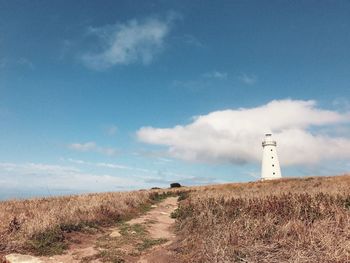 Lighthouse on landscape against sky