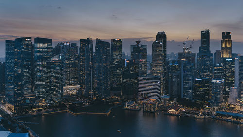 Illuminated buildings in city against sky during sunset