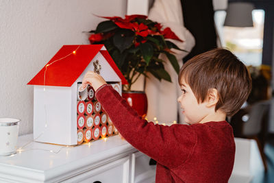 Cute boy decorating model house at home