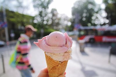 Cropped hand holding ice cream on street