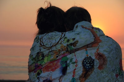 Rear view of woman standing against orange sky
