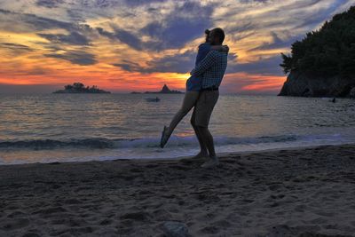 Man standing on beach against sky during sunset