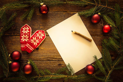 Close-up of christmas decorations with blank paper on pencil on table