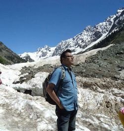 Man looking away while standing on rock against mountains