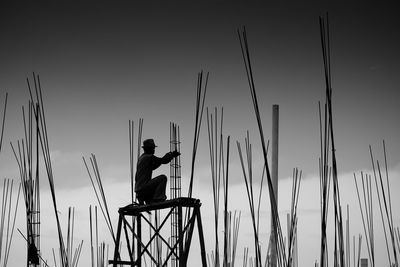 Low angle view of manual worker working against sky