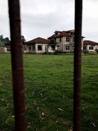 Barn on field by houses against sky