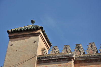 Low angle view of bird on building against blue sky