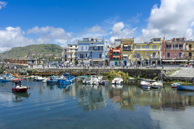 Boats moored in harbor against buildings in city