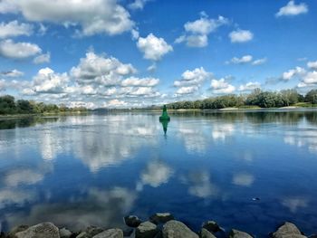 Rear view of man standing by lake against sky