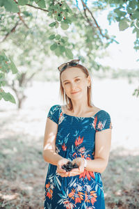 Beautiful caucasian woman with handful of mulberries at farm outdoor. 