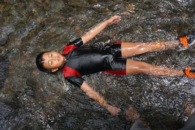 High angle view of boy lying in river