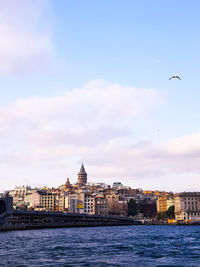 View of buildings at waterfront against cloudy sky