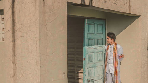 Man standing at doorway against wall 