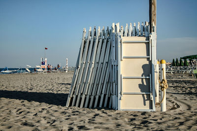 Hooded chairs on beach against clear sky