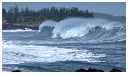 Waves splashing on sea against clear sky