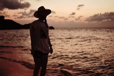 Man standing on beach against sky during sunset