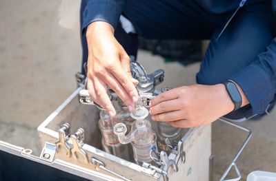 Environment officer with test tube sampling, stack of boiler in factory.