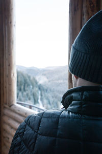 Rear view of man looking through window