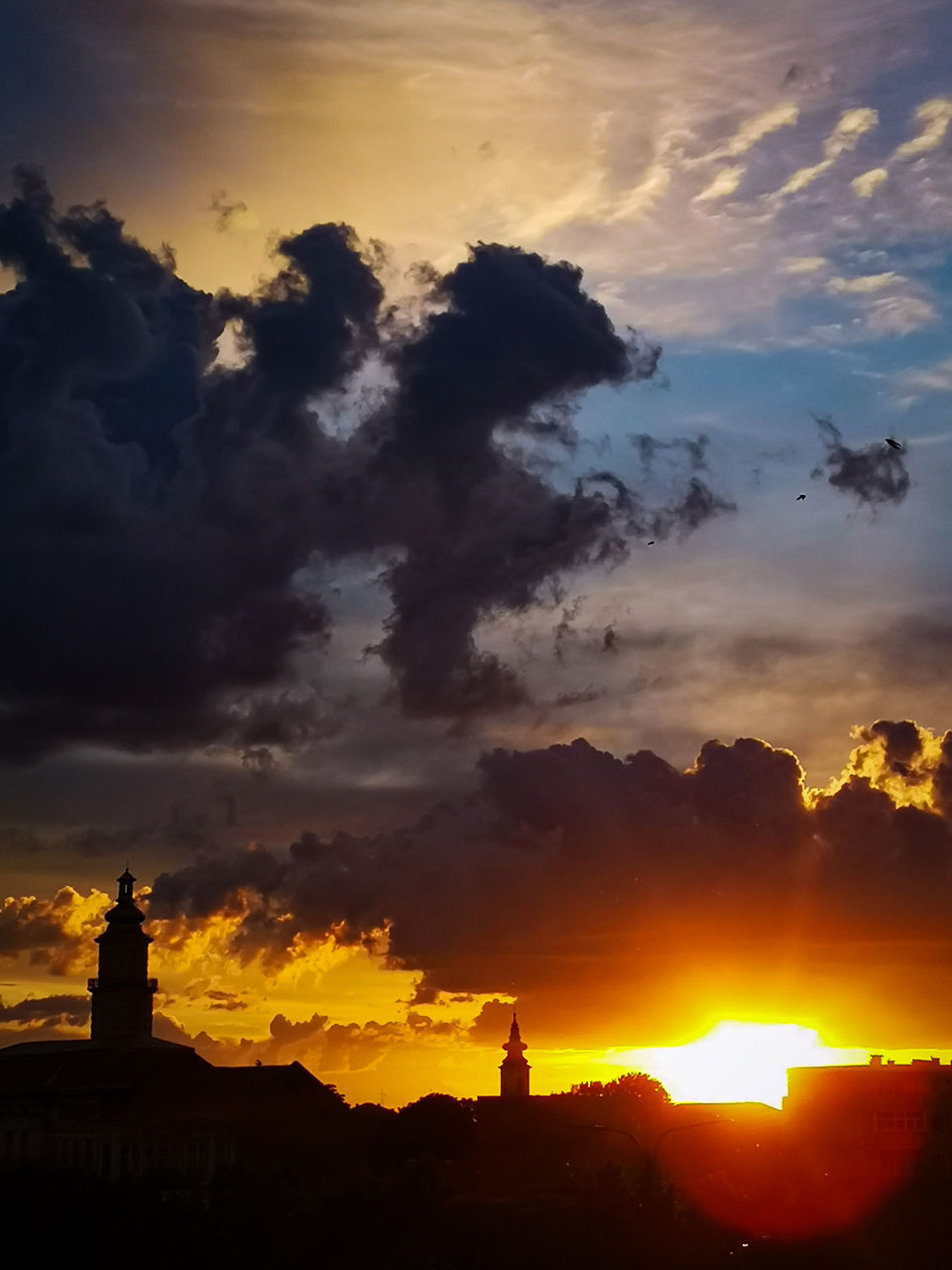 SILHOUETTE BUILT STRUCTURES AGAINST DRAMATIC SKY DURING SUNSET