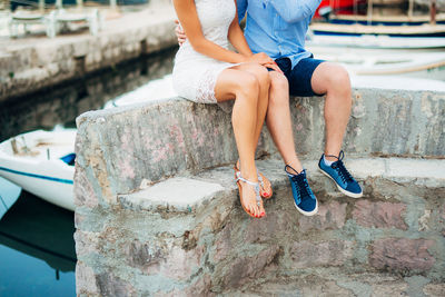 Low section of woman sitting on retaining wall