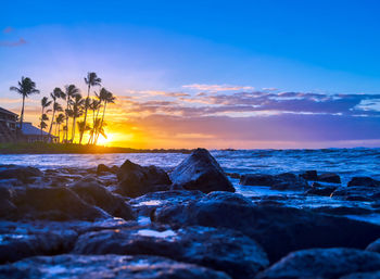 Rocks by sea against sky during sunset