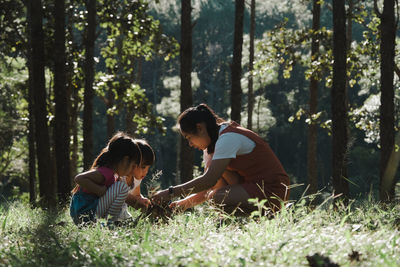 Mother setting bonfire with kids at forest