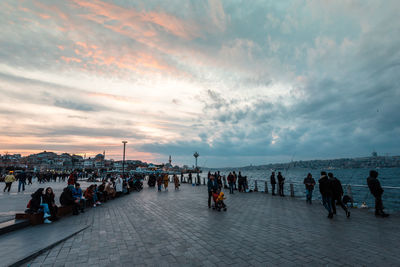 People on beach against sky during sunset