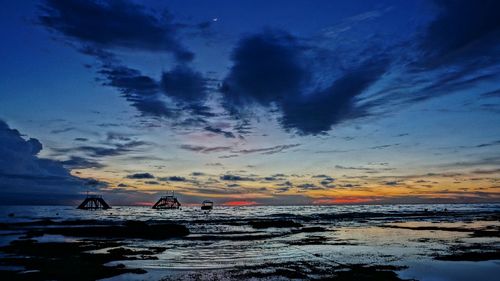 Silhouette people on beach against sky during sunset