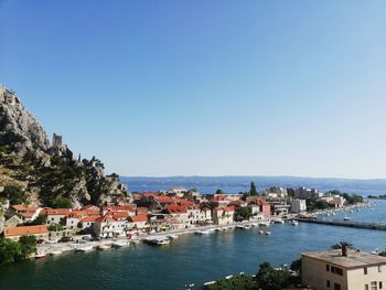 Townscape by sea against clear blue sky