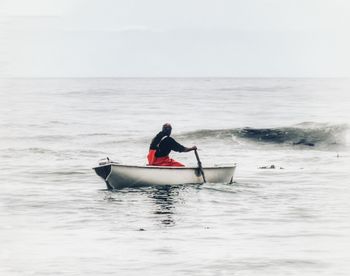 Man in boat on sea against sky