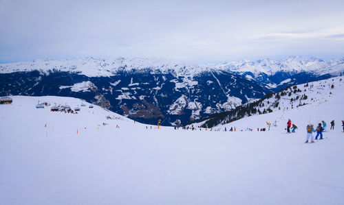 People on snow covered landscape against sky