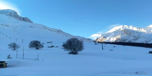 Scenic view of snow covered mountains against blue sky