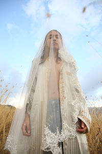 Low angle view of woman with veil standing against sky