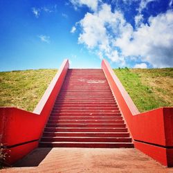 Red staircase against cloudy sky