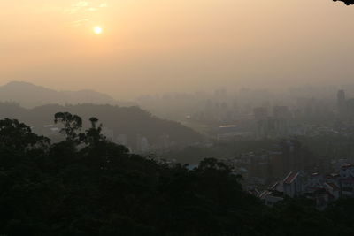 Trees and cityscape against sky during sunset